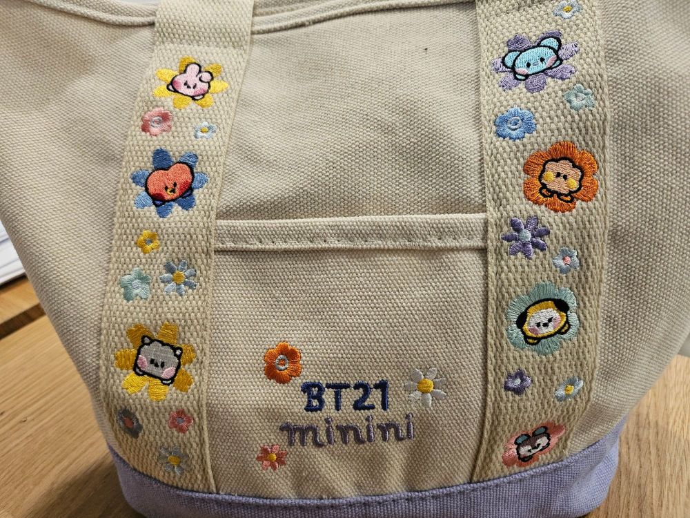 BT21 minini embroidered tote with BT21 characters surrounded by colorful flowers.