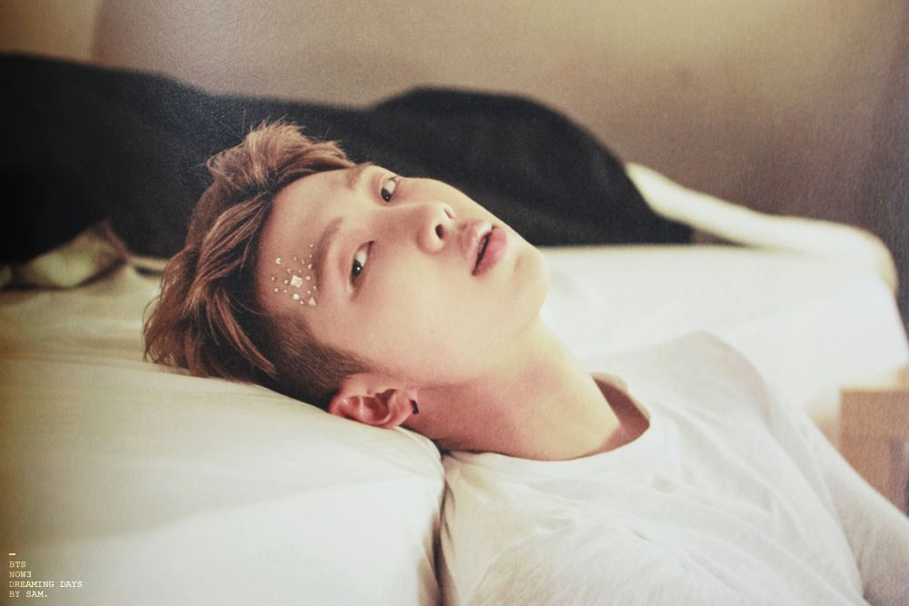 Namjoon in a white tee, making really intense eye contact with me while leaning against a bed with jewels applied to his forehead (lol)