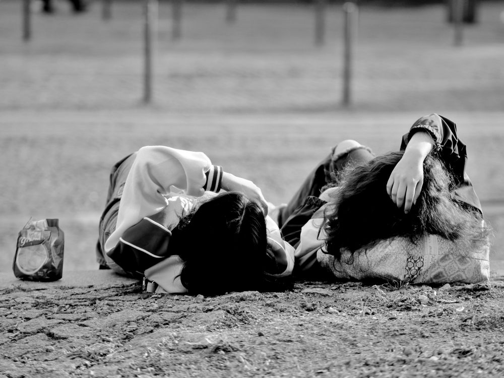 Zwei junge Frauen liegen auf einer Treppe und chillen in der Sonne. 