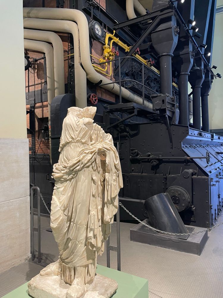 A headless statue from ancient Rome standing in front of the ductwork of a 75yo steam boiler.