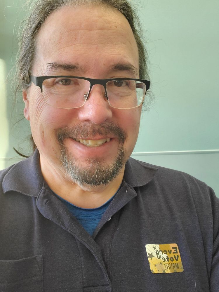 Me smiling with my voter sticker on my shirt. 
