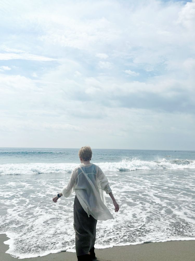 波打ち際に立つ私の後ろ姿の写真。