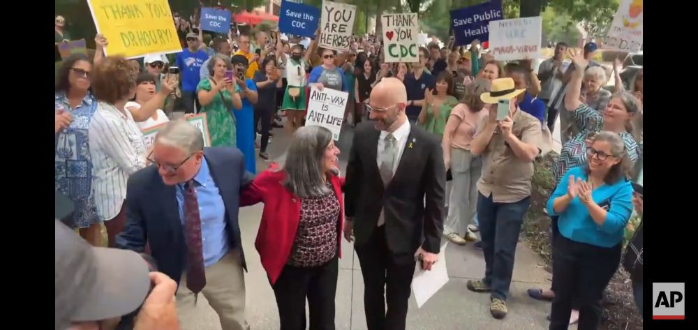 Debra Houry, Demetre Daskalakis, and Daniel Jernigan surrounded by crowd holding signs like "thank you CDC" and "save public health"