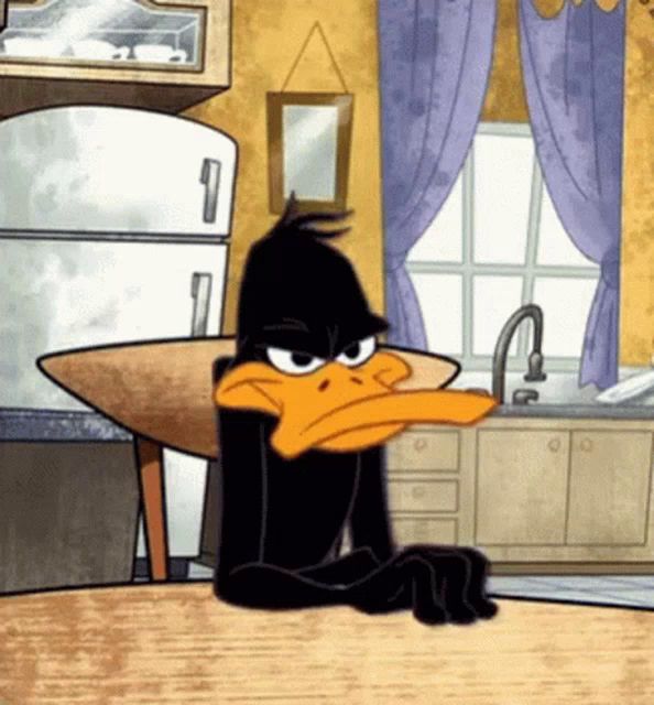 a cartoon of daffy duck sitting at a table