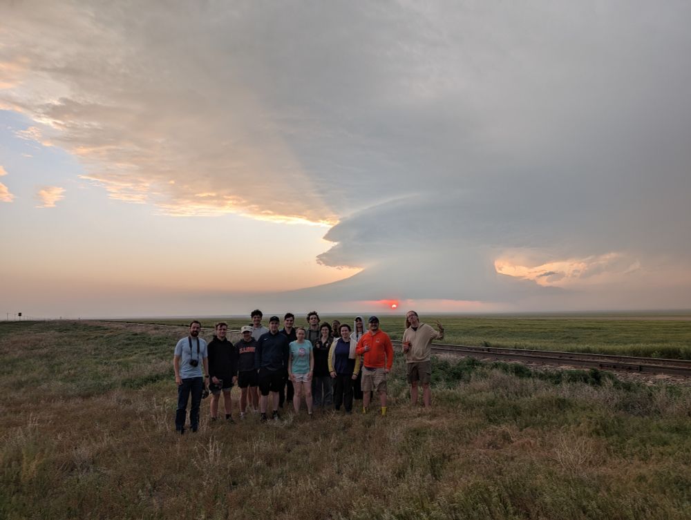 UIUC undergraduate students stand in front of a supercell at sunset