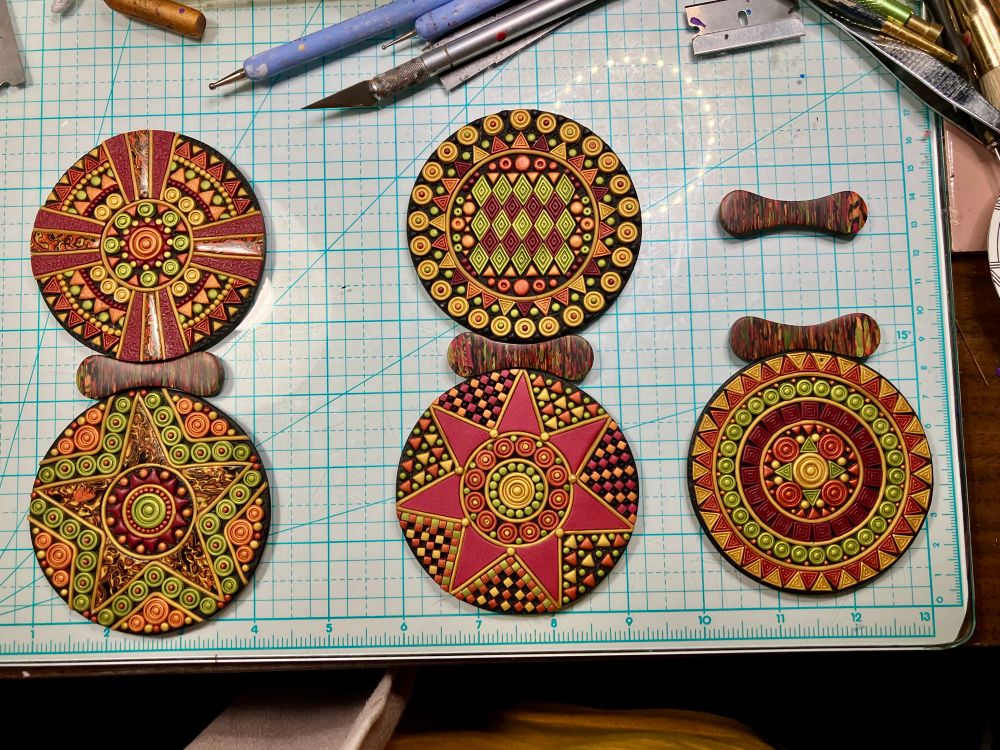 Five polymer clay disks with raised geometric designs.