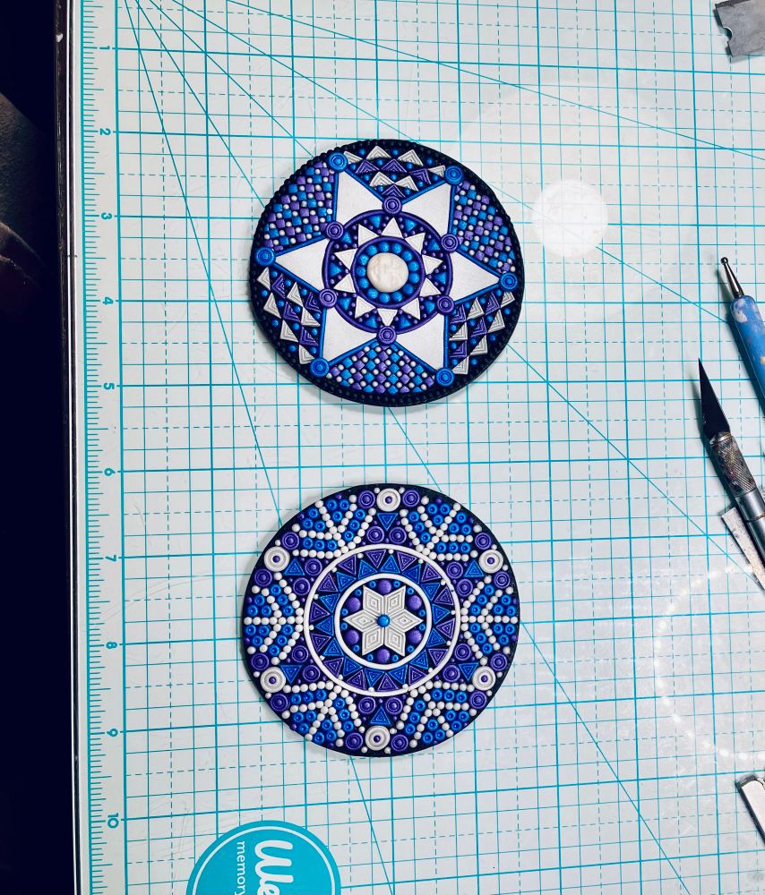 Two polymer clay disks with raised geometric designs.