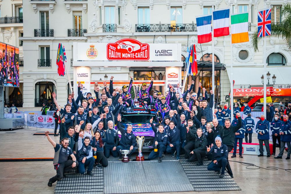 Picture of a team of people celebrating around the winning car of the 90th Monte Carlo Rally.