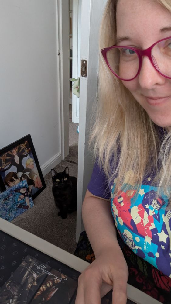 Tortoise shell cat watching over a lady at her desk.