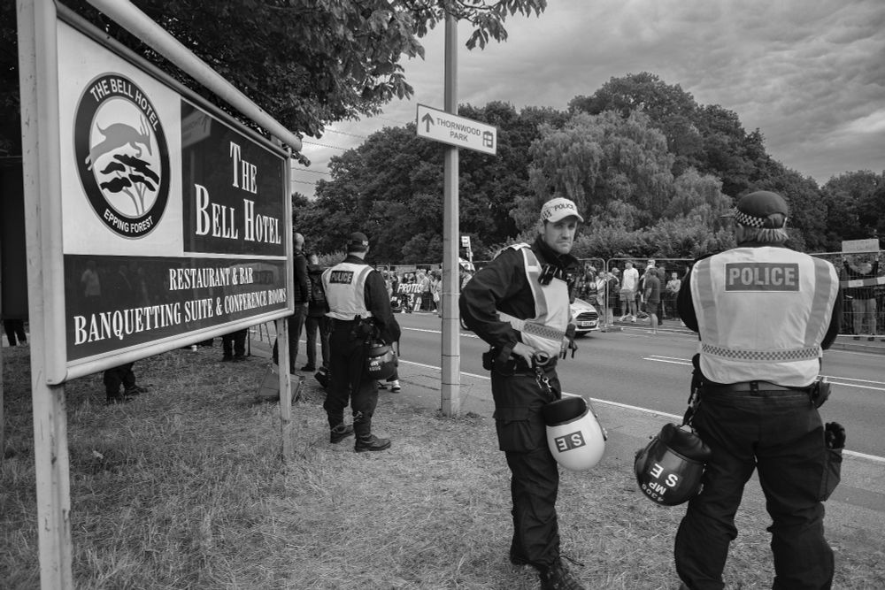 Police outside the Bell Hotel in Epping with anti-asylum protesters visible across the road