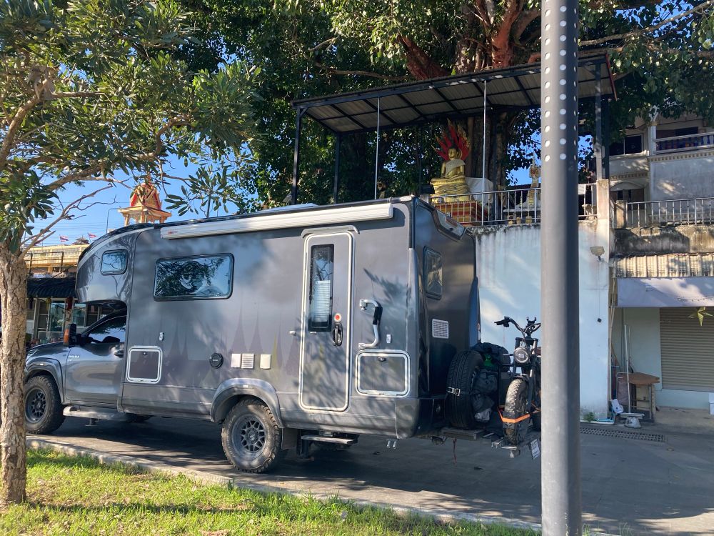 Een motor achterop de zwarte camper.