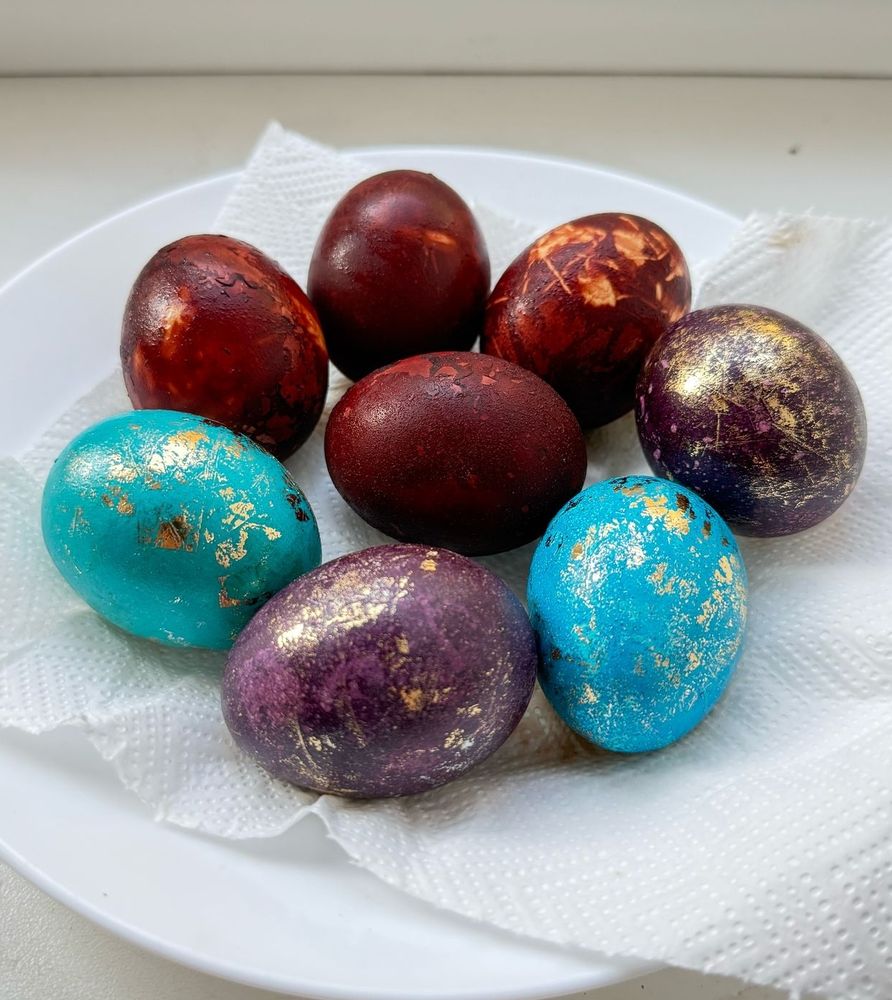 8 Easter eggs, half are reddish brown, two are blue with golden sparkles and two are purple with golden sparkles.