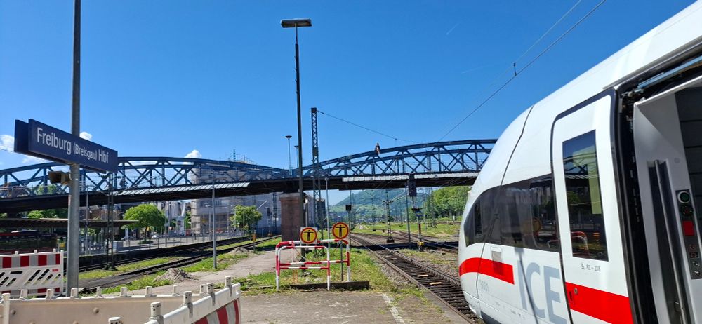 Bahnsteig in Freiburg mit ICE vorne und Blauer Brücke im Hintergrund. 
