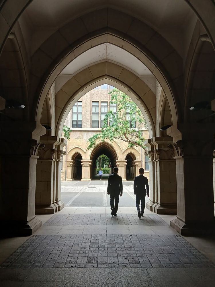 A photo of two figures walking through an archway