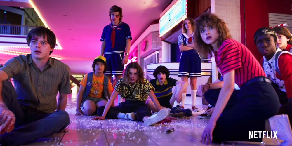 The Stranger Things gang hanging on the floor of a neon mall.