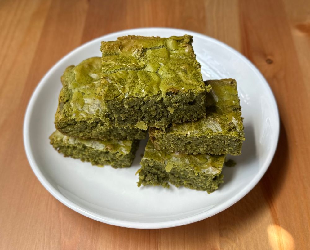 Five stacked matcha greenies/brownies eloquently plated on a white dish. They beckon you to eat more after four of them have been eaten.