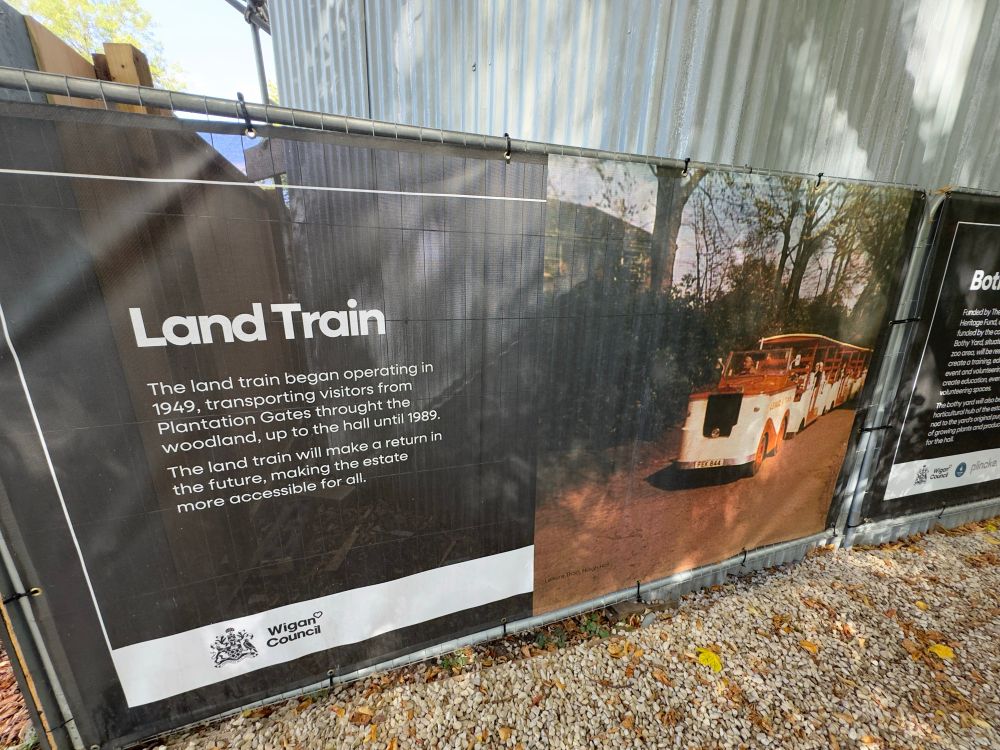 A large advertisement for an upcoming renovation project to a local park titled “Land Train”. The remaining description is as follows.

The land train began operating in 1949, transporting visitors from Plantation Gates throught the woodland, up to the hall until 1989.
The land train will make a return in the future, making the estate more accessible for all.