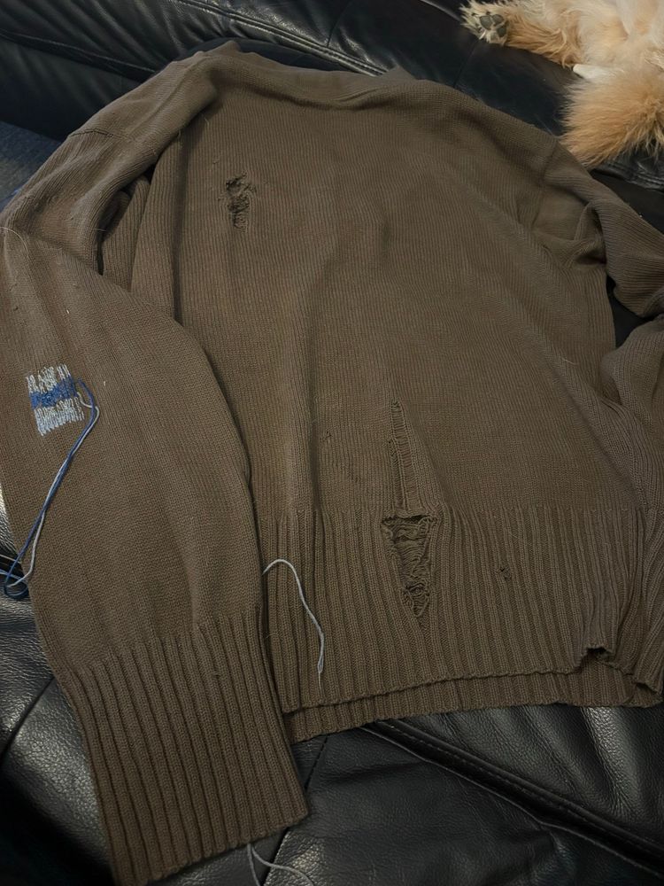 Brown wool sweater with several large holes. A new rectangle of grey and blue Swiss darning is covering a medium size hole that was on the arm. Fuzzy Muddy waters is just visible in the upper right corner.