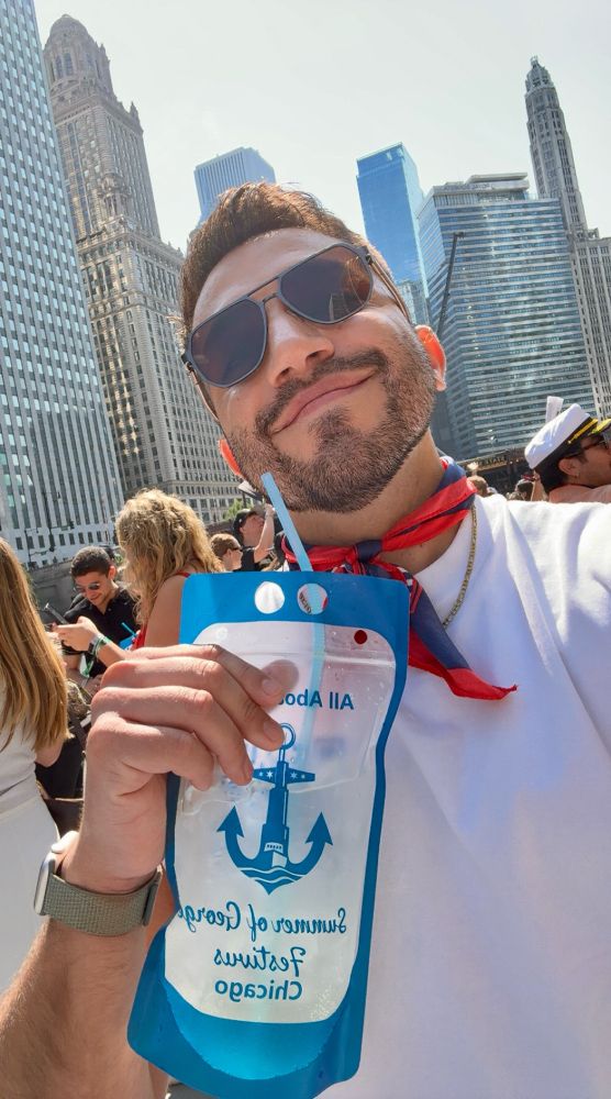 selfie of me on a boat on the chicago river wearing a white tank/crop top and a delta airlines ascot holding a tequila caprisun drink 