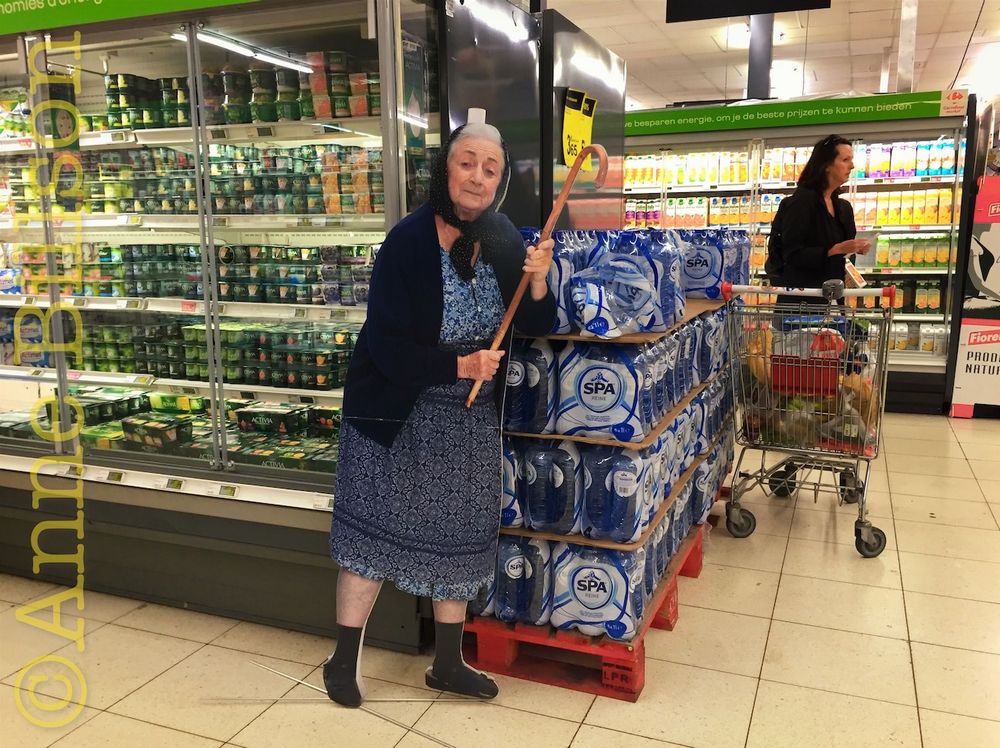 An old lady wields a walking-stick next the yogurt section of a supermarket. On closer examination, it becomes apparent that she is a life-size cardboard cutout, advertising something or other, though God knows what.