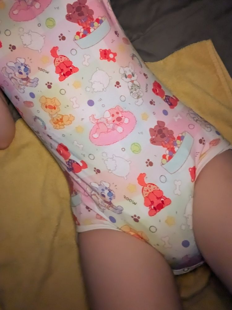 Cute puppygirl laying in bed wearing a onesie with a bunch of cute puppies on it. She's definitely not wearing a diaper. Don't pay attention to the towel underneath her either.