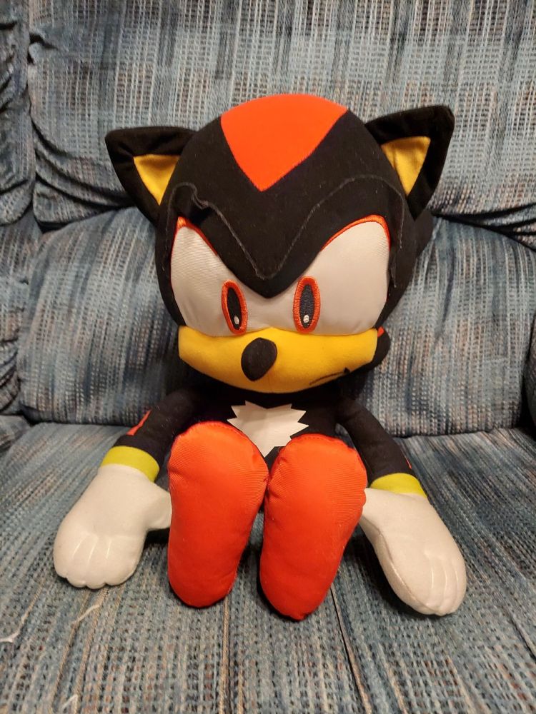 A plush Shadow the Hedgehog sitting on a blue couch.