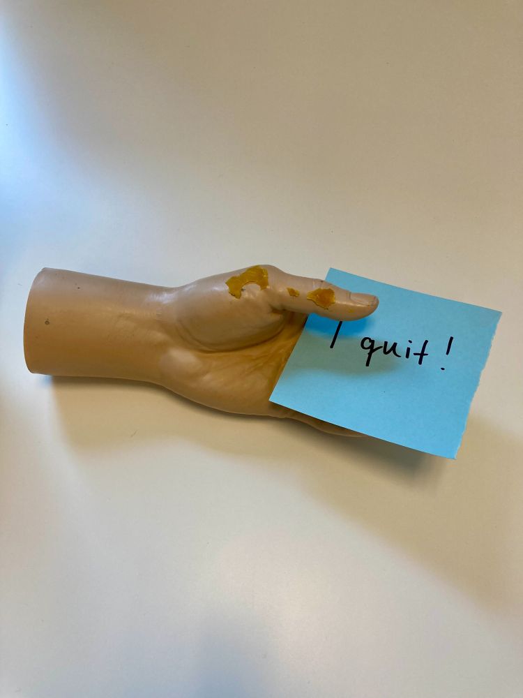A picture of the hand holding a post-it note with "I quit!" written on it