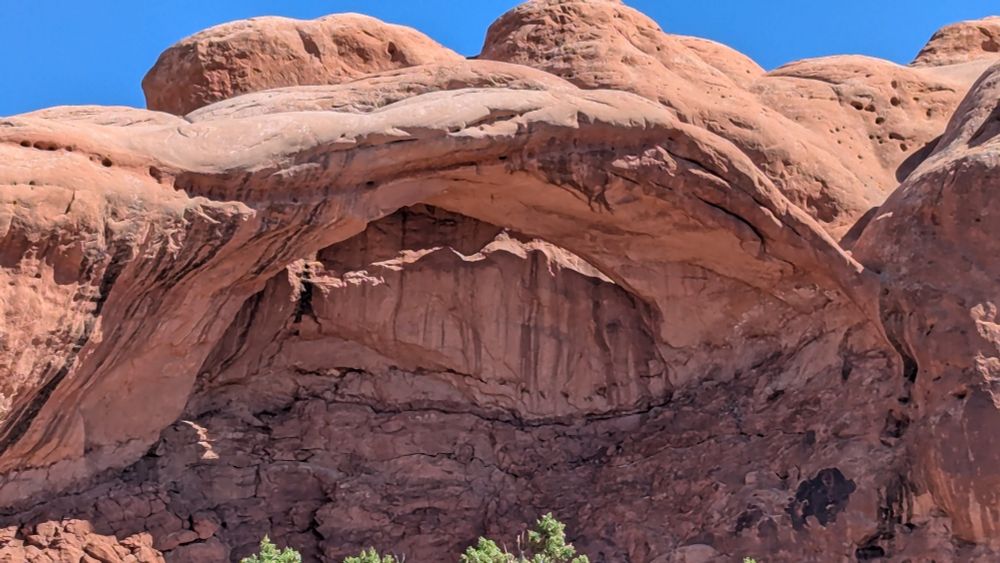 A natural rock arch provides shade from the desert sun.
