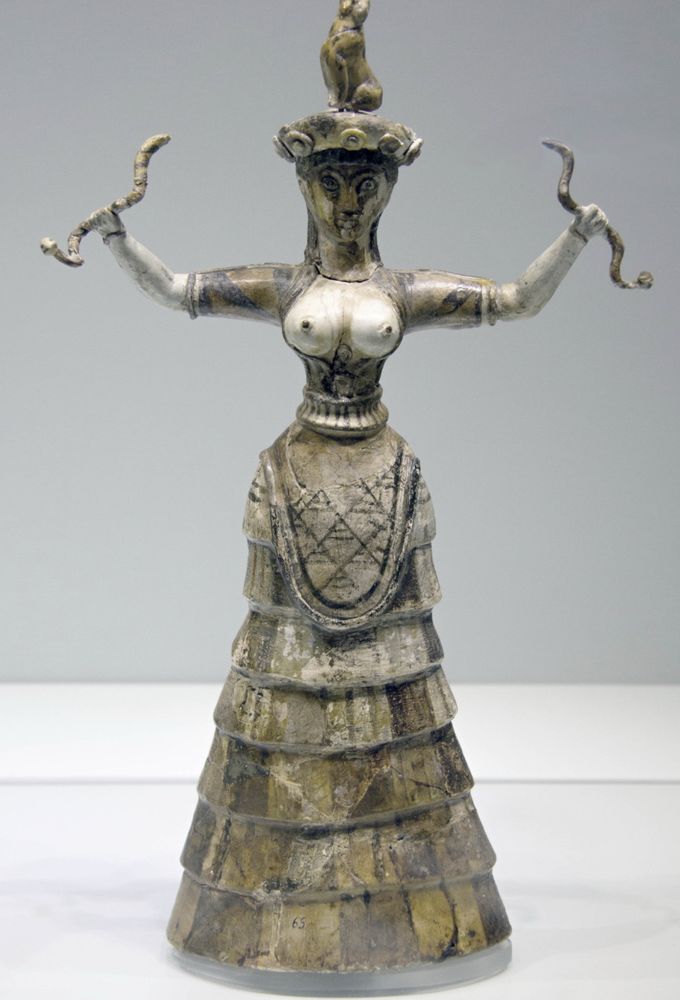 The Minoan snake goddess sculpture. Bare chested woman arms outstretched holding snakes.