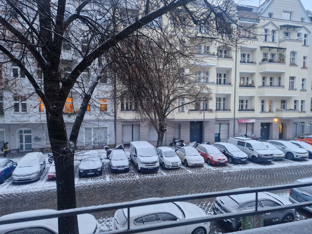 Thin cover of snow on cars parked on a city street