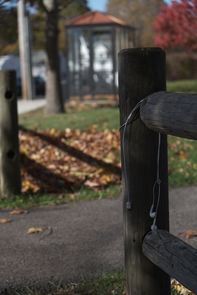 a fence post with wired headphones draped and abandoned on the post.