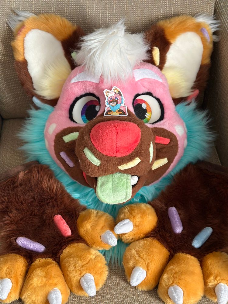 a head of pink sprinkledog and his paws, with a cute sticker sitting on his nose!
