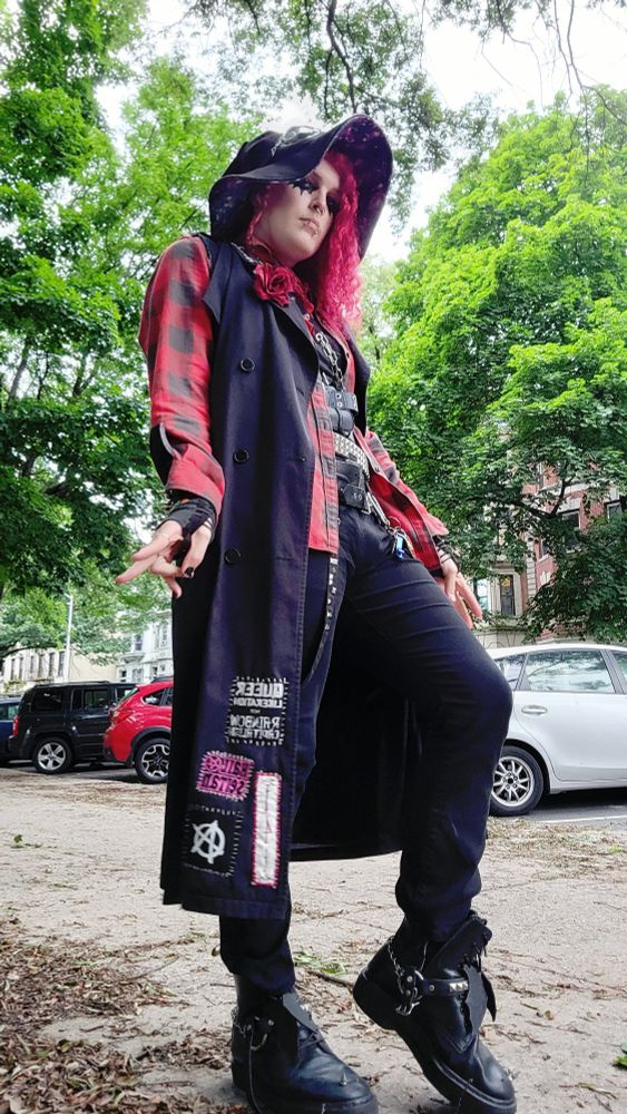 lilith (goth trans woman with red hair) wearing a big sleeveless trench coat and a red flannel underneath