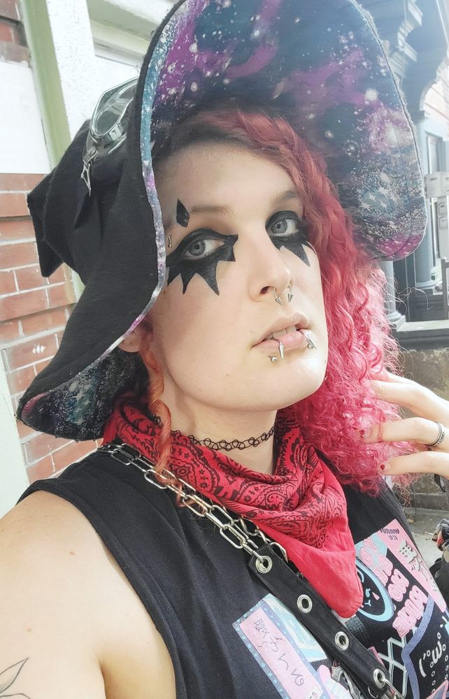 lilith (goth trans woman with red hair) selfie uhhh shes wearing a red bandana and has her left hand brushing her hair out of the way
