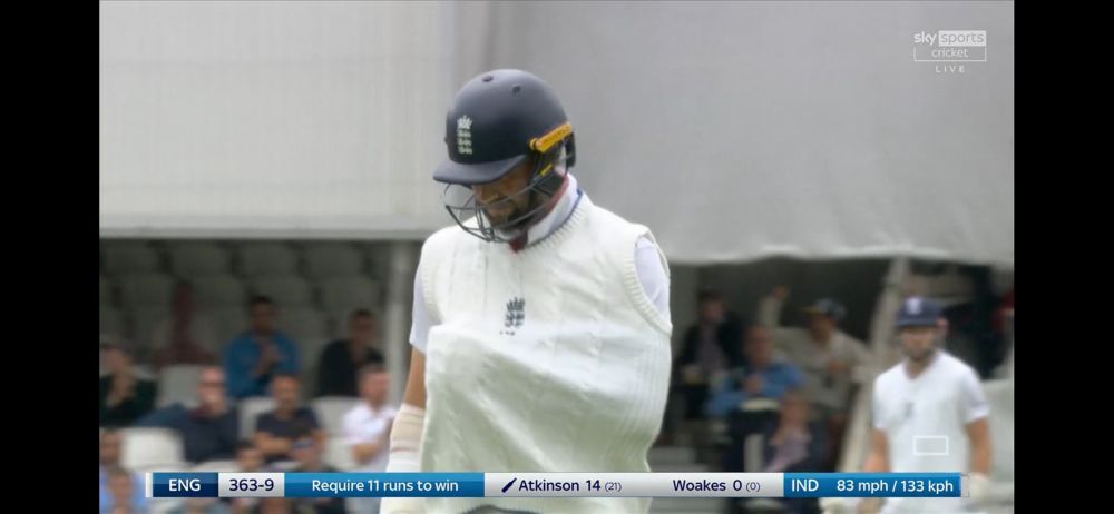Chris Woakes stands grimacing in pain, his arm in a sling inside his cricket… strip? What do you call it? England still need 10 runs to win the match (and nine to win the series), but India need one wicket to win the match and tit the series.