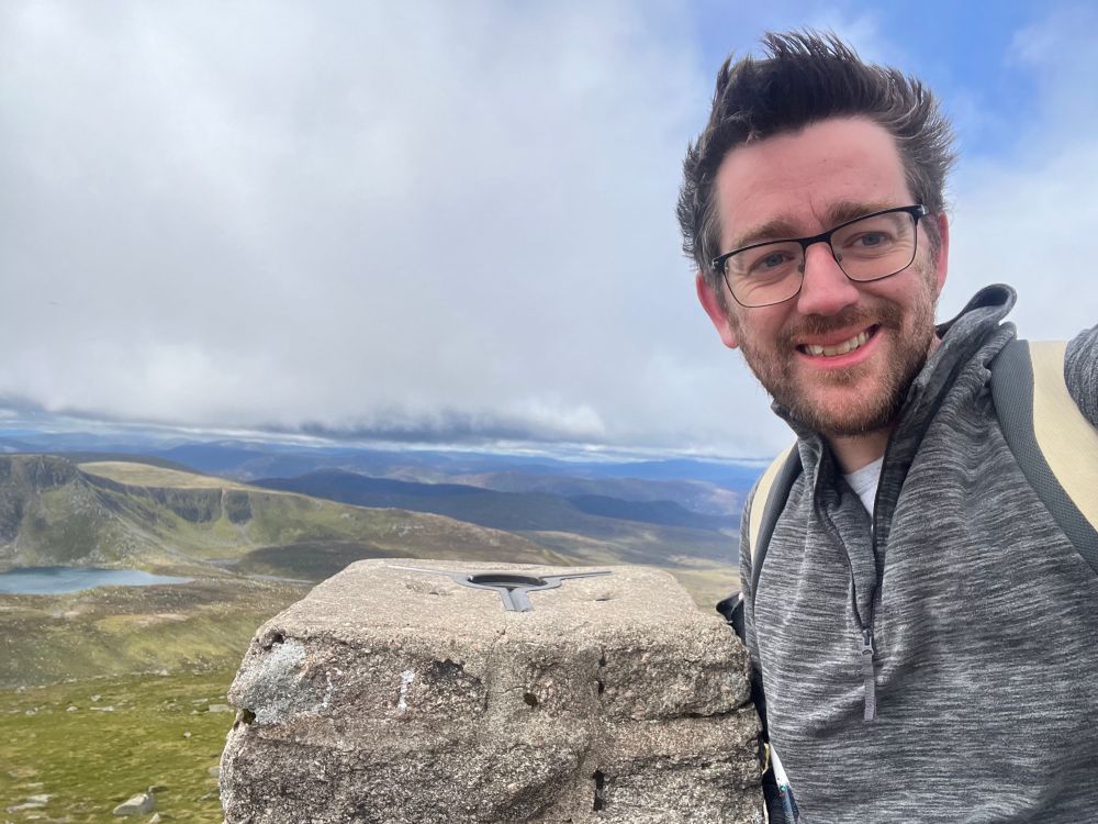 Me on top of Lochnagar, holding on for dear life to the trig point in the worst winds I’ve ever felt on a hillwalk.