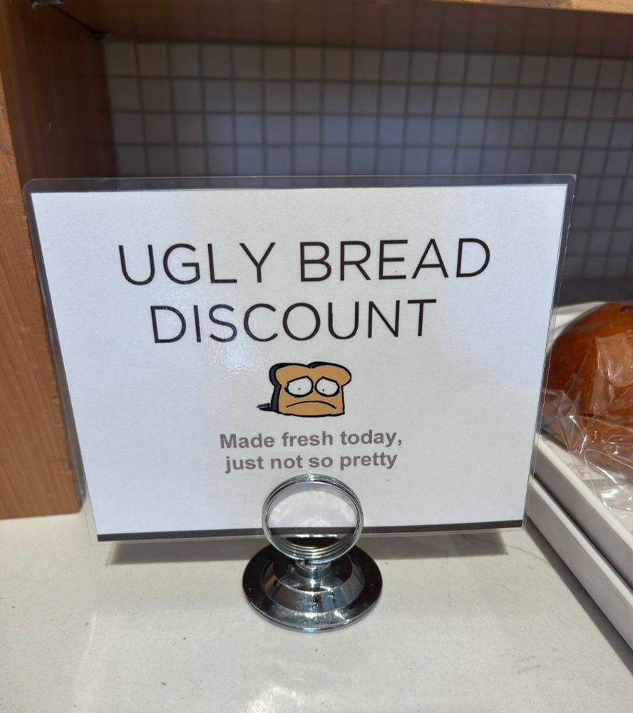 A sign at a super market or grocery store that reads "Ugly Bread Discount" made fresh today just not so pretty. 