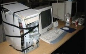 An image of a very damaged desktop computer that has been beat, taken apart and is held together with electrical tape  logging on