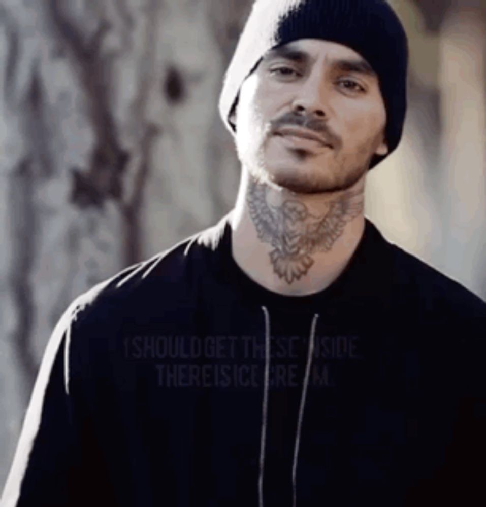 a man with a tattoo on his neck wearing a beanie and a black shirt .