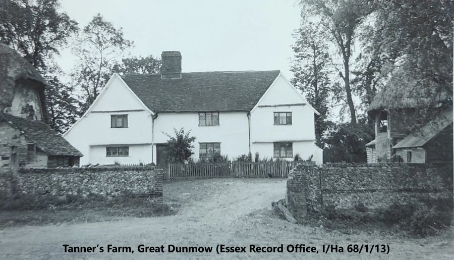 Black and white photo of a two-storey, four-bay farmhouse with lime-washed walls, a tiled roof, and single large chimney stack. It is set back from a wide opening in a stone wall. Parts of other buildings can be seen on both left and right.