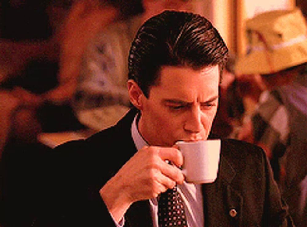 a man in a suit and tie drinking from a white cup