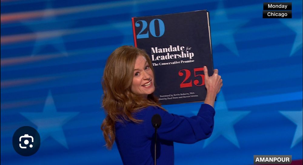 Mallory a McMorrow holding up a giant copy of Project 2025 during the DNC
