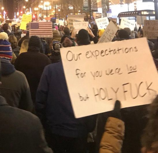 Person holding up a sign reading Our Expectations for you were low but HOLY FUCK