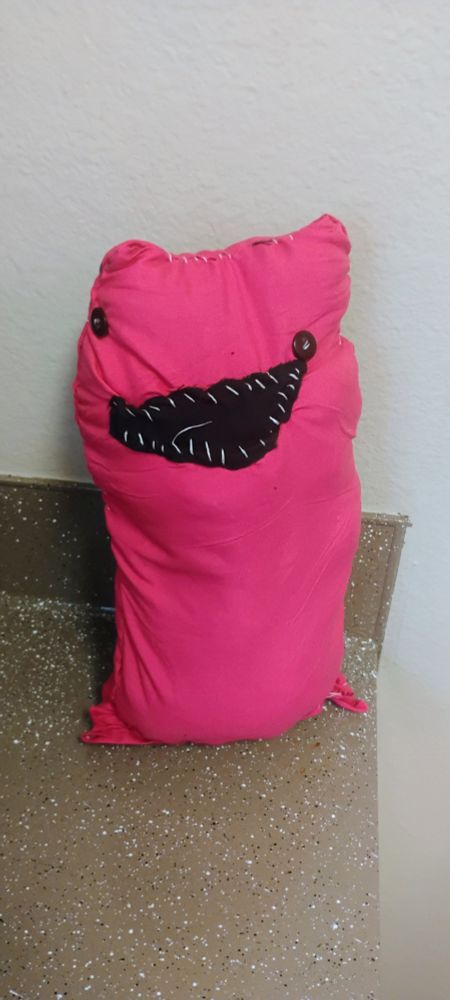 the same plushie but actually sewed up

the mouth has been given a jagged white stitching resembling monster teeth

the eyes are horribly asymmetrical 

and the shape of the plushie itself has warped horribly 

overall it looks very silly and grotesque. like something you'd see in a horror movie