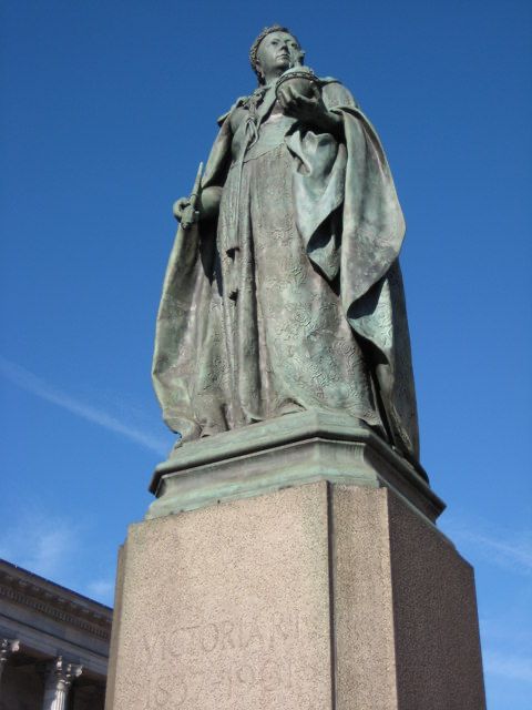Bronze statue of Queen Victoria in robes holding an orb and staring into the middle distance, from Victoria Square, Birmingham