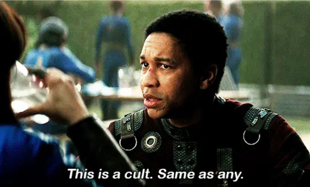 A scene from Fallout series on Amazon where Maximus is telling Lucy that the vault they’re in is suspiciously happy all the time. He says “This is a cult. Same as any.”