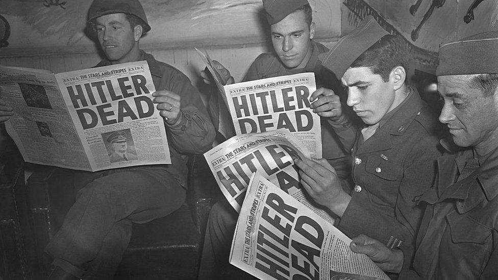 picture of WW2 USA troops reading newspapers with "HITLER DEAD" on the front page