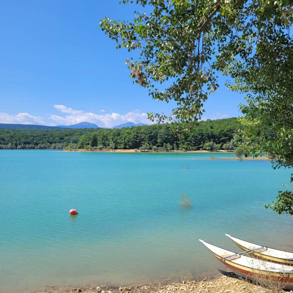 Un beau lac bleu, 2 barques au 1er plan, forêt au fond, ciel bleu