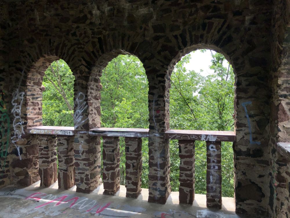 View from within the third level out through a triple archway to treetops in sunlight.