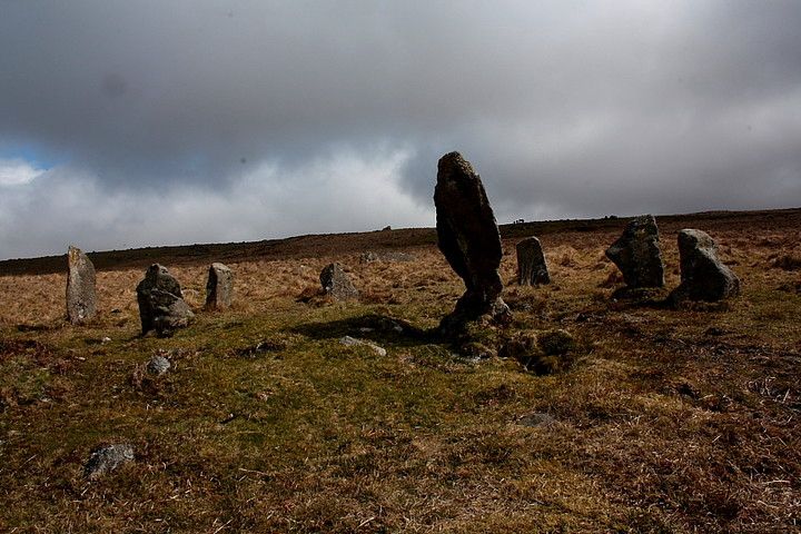 Greeny brown moorland with a stone circle - one of the stones is larger than the others & is shaped like a leaning spear head